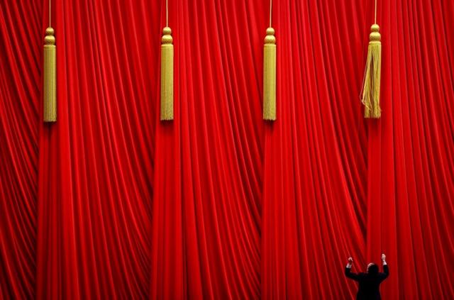 在中国北京举行的全国人民代表大会第五次全体会议之前,一名男子正在拉幕帘(2023年3月12日资料照片)。