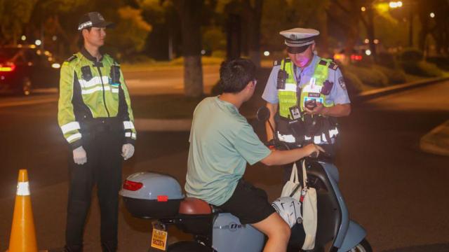 2023年8月2日,浙江省舟山市交警对未戴安全帽的电动自行车驾驶人进行安全教育。