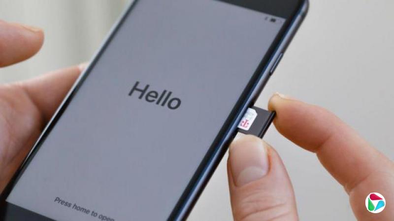 一个人把SIM卡插入手机,萤幕上显示“Hello”。
