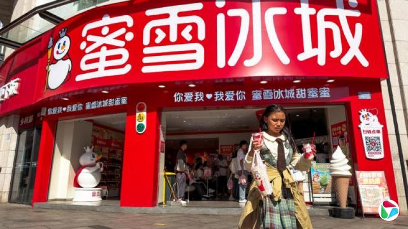 2026年4月,中国重庆一家蜜雪冰城门店。一名女孩手持两个新地冰淇淋和一杯饮品,从店前走开。