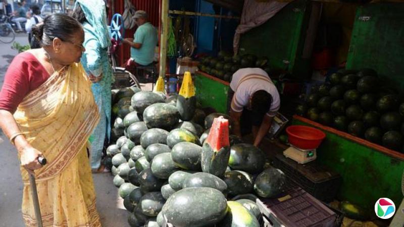 2026 年 5 月 5 日,印度西里古里(Siliguri)一处市场区内,一名临时路边摊贩正在贩售夏季水果西瓜,摊位上堆放着多颗西瓜,供来往顾客选购