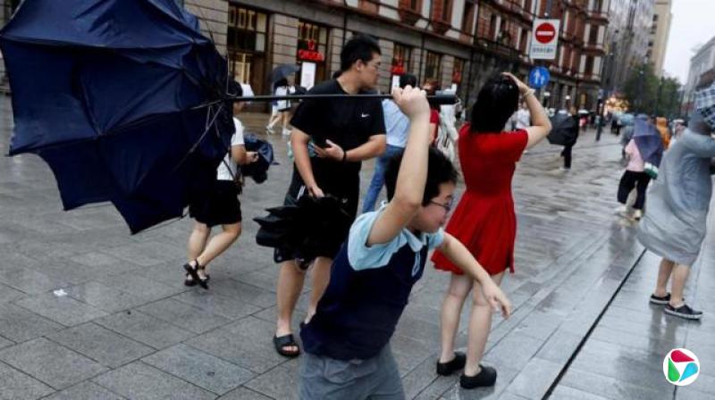白海豚台风来临前风势增强之际,上海街头有民众撑伞行走,其中一名男童正试图抓紧一把被吹翻的雨伞(9/8/2026)