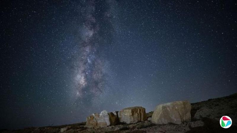 银河在辽阔的繁星夜空中清晰可见,前景则是地面和一些岩石。